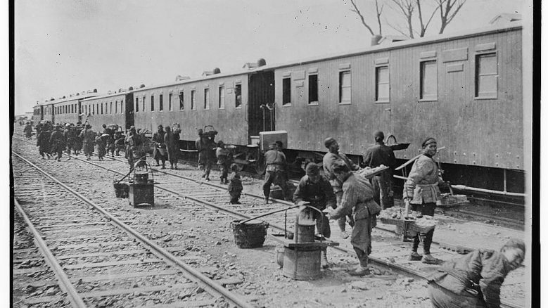 Black and white photograph depicting chinese rail road workers working at a rail road station